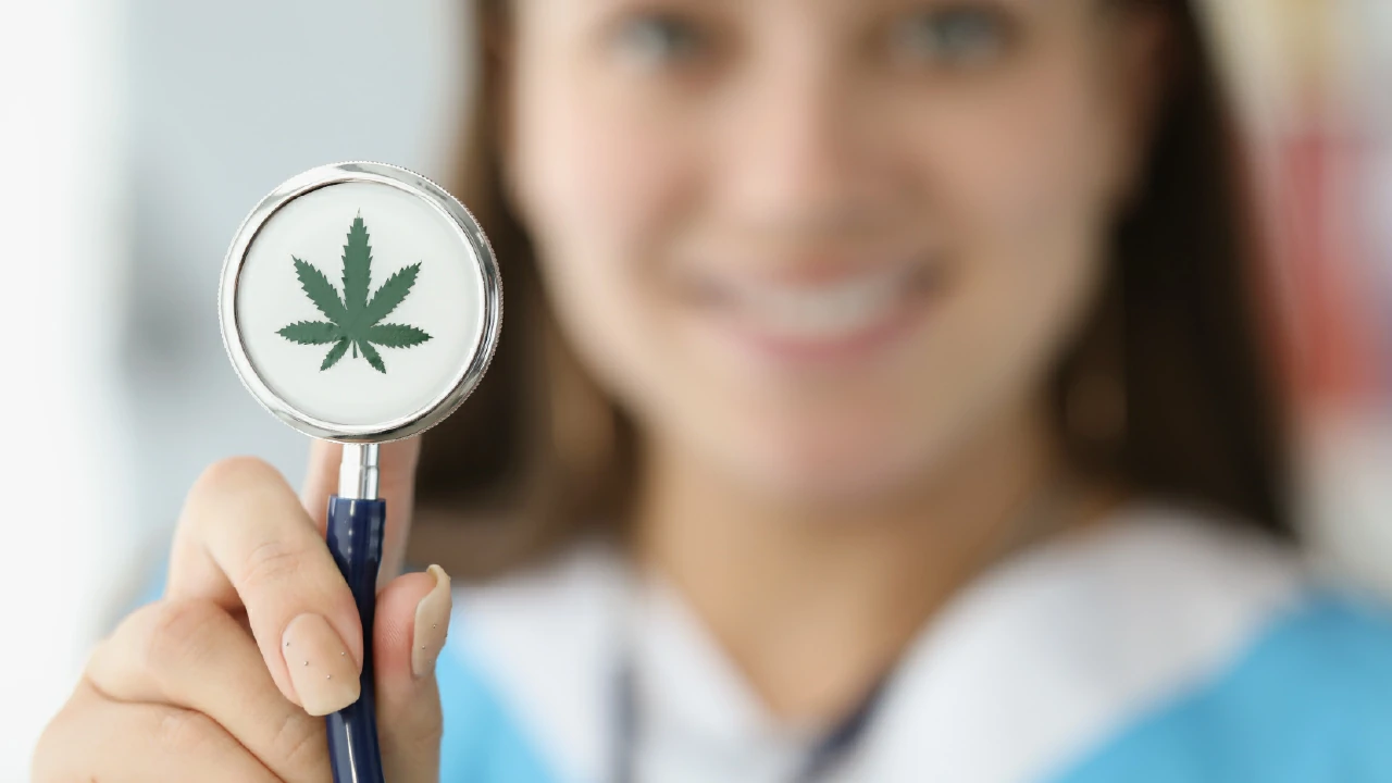 Doctor sosteniendo estetoscopio con hoja de marihuana dibujada de cerca